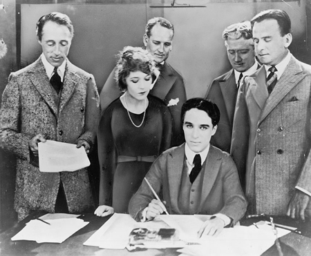 D.W. Griffith, Mary Pickford, Charlie Chaplin (sentados) y Douglas Fairbanks en la firma del contrato que estableció el estudio cinematográfico United Artists en 1919. Los abogados Albert Banzhaf (izquierda) y Dennis F. O'Brien (derecha) destacan.